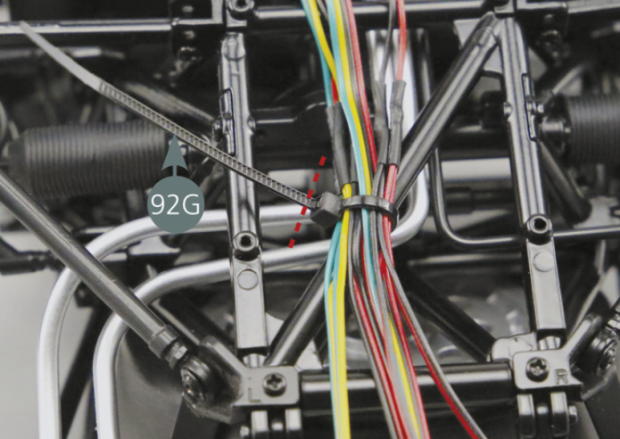 Position the headlight cables (18D) on the diagonal bar of the lower frame (5A) and secure these by using the clamp (92G) and tightening it (yellow arrow). 