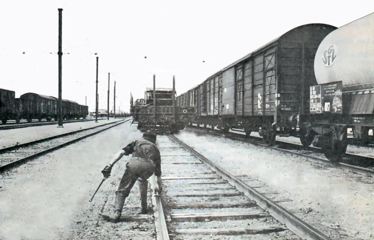 Es sind die 1950er Jahre. Dieser Eisenbahner verrichtet eine sehr gefährliche Arbeit in einem Rangierbahnhof. Die Waggons steigen ungehindert vom „Buckel“ ab, wobei er vor ihnen hergehen und einen Metallblock vor die Räder stellen muss, um den Wagen abzubremsen und für einen sanften Stopp am Ende des Zuges zu sorgen, der bereits zusammengestellt und bald zur Abfahrt bereit ist.© IXO Collections SAS - Tous droits réservés. Crédits photo ©&nbsp;Collection Trainsconsultant-Lamming