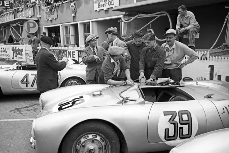 Los boxes de Porsche en las 24 Horas de Le Mans de 1954. Al fondo, con traje y corbata, Ferry Porsche charla con su director técnico, Fritz Huschke von Hanstein, entre dos 550.© IXO Collections SAS - Tous droits réservés. 