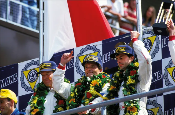 De gauche à droite : l’Américain Hurley Haywood, l’Italien Mauro Baldi et le Français Yannick Dalmas, vainqueurs de 24 Heures du Mans 1994. Ils sont vus ici lors de la célébration de la victoire sur le podium. © IXO Collections SAS - Tous droits réservés. 