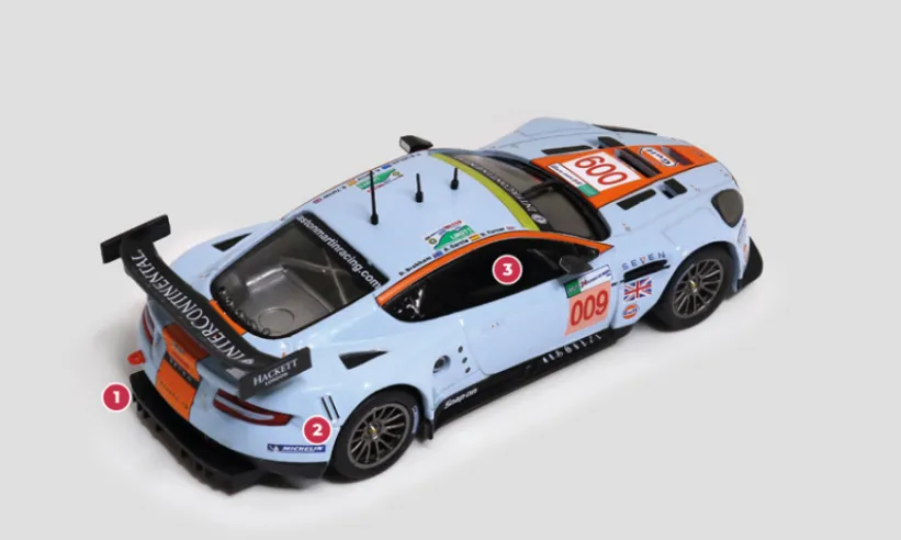 1. En plus de l’aileron monté à l’arrière, l’Aston Martin DBR9 est équipée d’un grand et proéminent extracteur d’air.2. La boîte de vitesses séquentielle XTrac est montée en bloc avec le différentiel arrière pour mieux équilibrer les masses de la voiture.3. La caisse est renforcée par un arceau de sécurité visible dans l’habitacle.© IXO Collections SAS - Tous droits réservés.