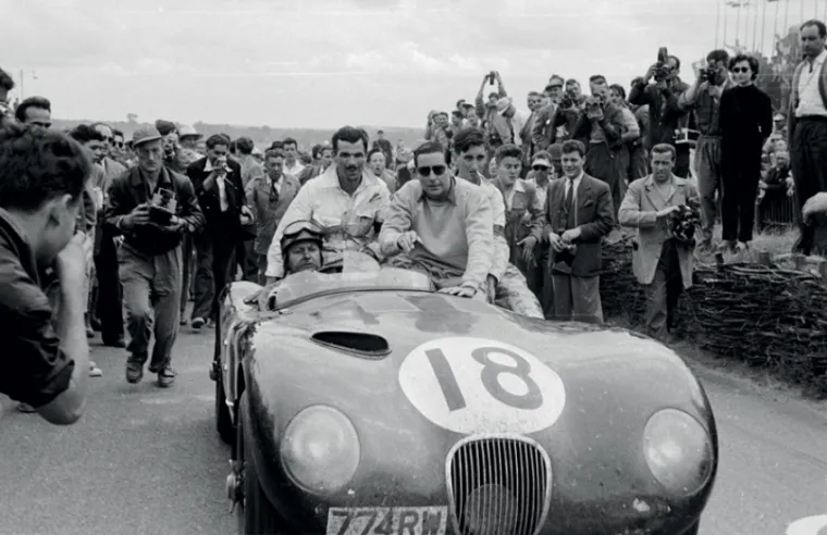 Der siegreiche Typ C in Le Mans 1953 mit Tony Rolt (rechts, dunkle Brille) und Duncan Hamilton (am Steuer). Der zweite Platz wurde von Stirling Moss und Peter Walker in einem ähnlichen Typ C belegt.© IXO Collections SAS - Tous droits réservés.