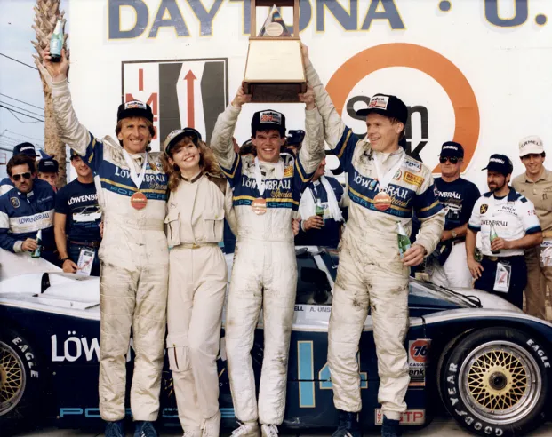 Podium de la première victoire de la Porsche 962 aux 24 Heures de Daytona 1986. À gauche, Derek Bell ; au centre, le très jeune Al Unser Jr. (moins de 24 ans à l’époque) ; à droite, le pilote n° 1 et directeur de l’équipe Al Holbert.© IXO Collections SAS - Tous droits réservés. 