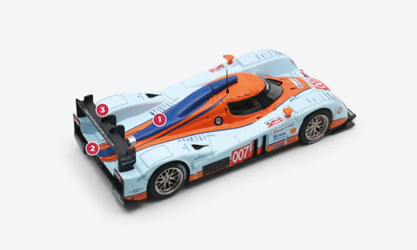 1. Der 6-Liter-V12-Motor, bereits im DBR9 verwendet, wurde nicht speziell für den B09/60 entwickelt, ist aber vom Standard-Motorblock von Aston Martin abgeleitet und profitiert daher vom größeren Lufteinlass, wodurch er 650 PS leisten kann.2. Der größere Motor bedeutete, dass das von Lola gelieferte Standardgetriebe nicht verwendet werden konnte, sodass es durch ein sequentielles X-Trac-Getriebe ersetzt wurde.3. Vor den 24 Stunden von Le Mans wurde die Karosserie mit verschiedenen aerodynamischen Verbesserungen versehen, von denen die auffälligste der Spoiler war, der durch Schwanenhalsbefestigungen gestützt wurde.© IXO Collections SAS - Tous droits réservés.&nbsp;